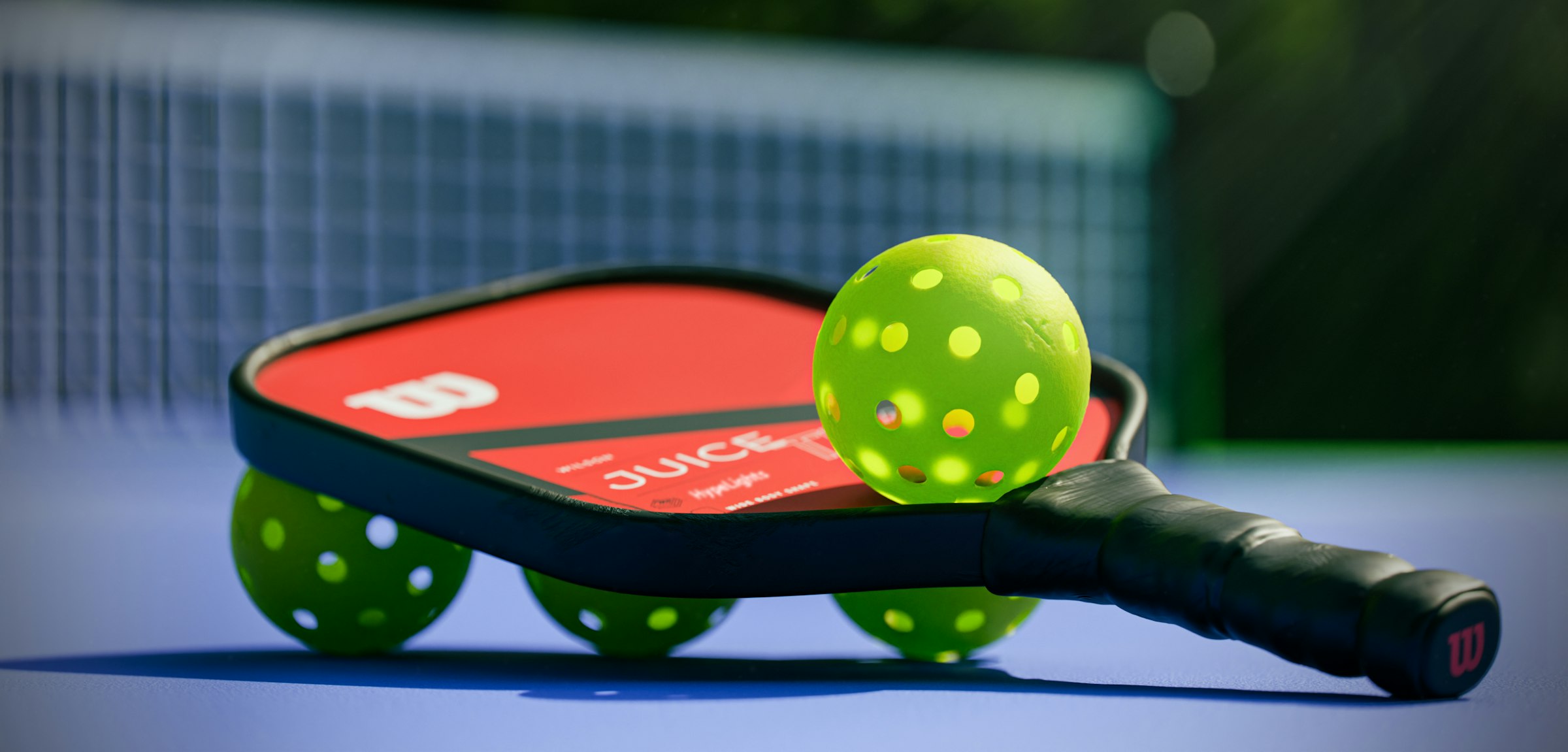 Pickleball paddle and balls on a blue court